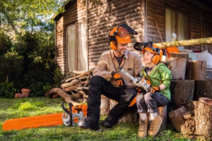 Tata i dziecko wspólnie spędzają czas przy pracy z drewnem, oboje ubrani w hełmy STIHL. Dziecko z radością trzyma pilarkę zabawkę MS 500i i ma na głowie zabawkowy hełm STIHL.